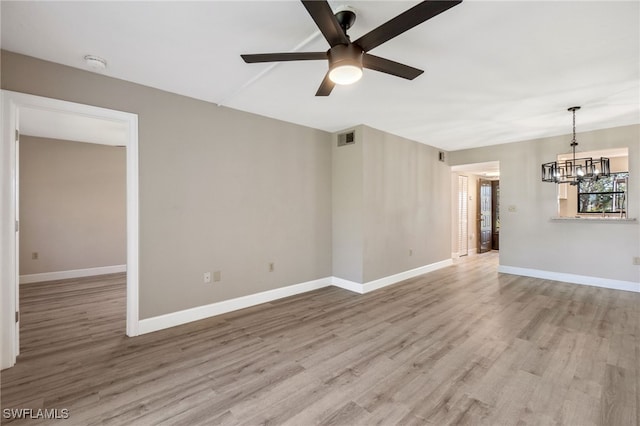 unfurnished room featuring ceiling fan with notable chandelier and light hardwood / wood-style floors