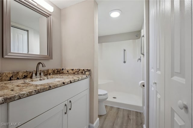 bathroom featuring wood-type flooring, vanity, toilet, and walk in shower