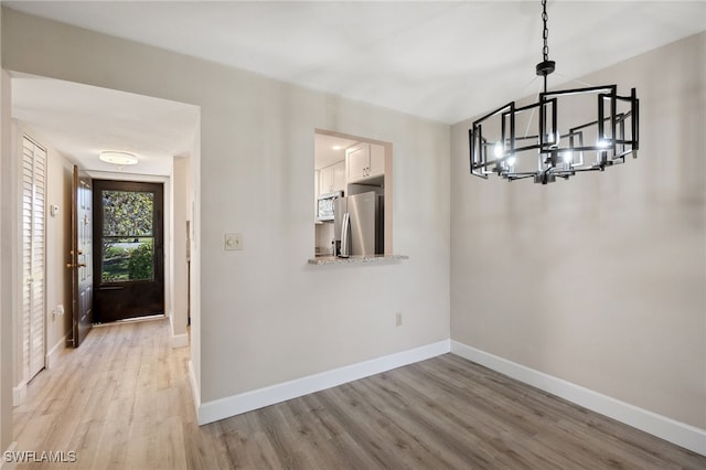 entryway with light wood-type flooring and a chandelier