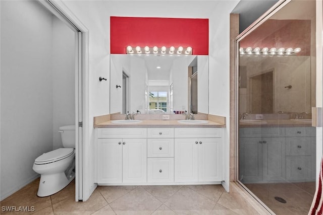 bathroom featuring tile patterned floors, toilet, a sink, a shower stall, and double vanity