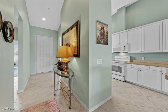 hall with baseboards, lofted ceiling, recessed lighting, and light tile patterned floors