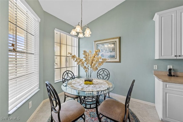 dining area with light tile patterned floors, vaulted ceiling, baseboards, and a chandelier