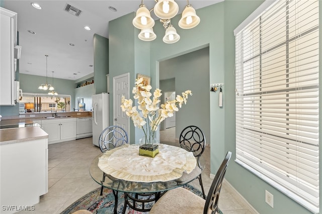 tiled dining area with a notable chandelier, a healthy amount of sunlight, and sink