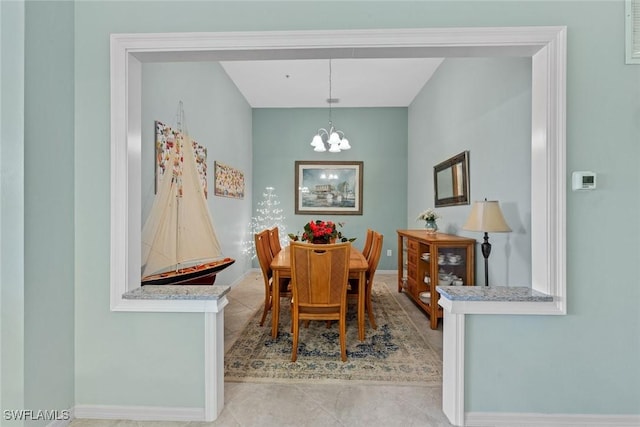 dining space featuring light tile patterned flooring, baseboards, and an inviting chandelier