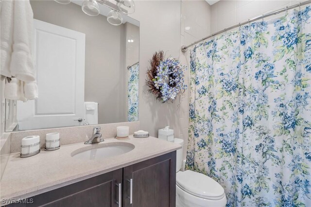 bathroom with a shower with shower curtain, vanity, and toilet