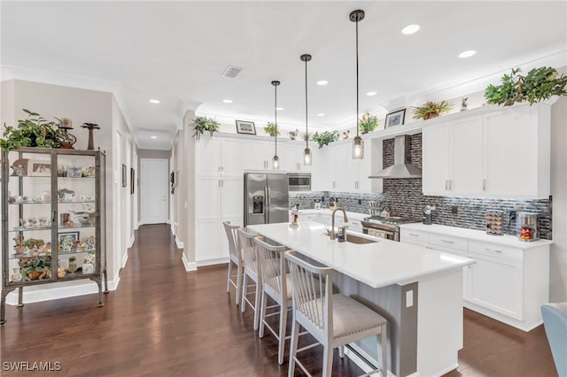 kitchen with a sink, visible vents, appliances with stainless steel finishes, decorative backsplash, and wall chimney exhaust hood