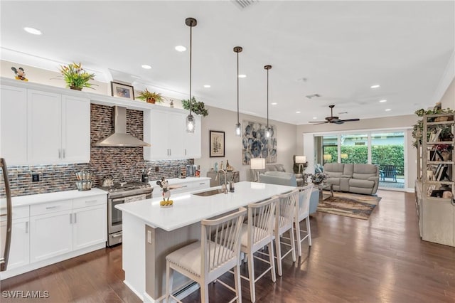 kitchen with a sink, wall chimney range hood, decorative backsplash, stainless steel gas stove, and dark wood finished floors