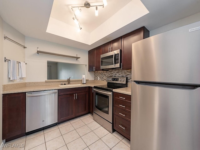 kitchen with sink, stainless steel appliances, a raised ceiling, backsplash, and light tile patterned floors