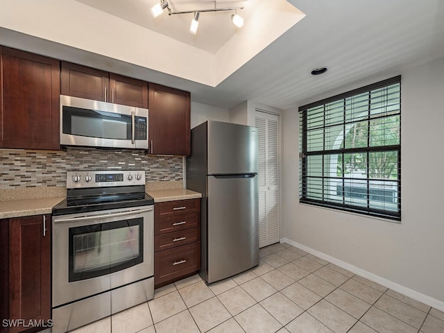 kitchen featuring rail lighting, decorative backsplash, light tile patterned floors, appliances with stainless steel finishes, and dark brown cabinets