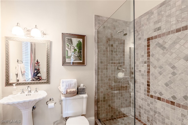 bathroom featuring toilet, a tile shower, and sink