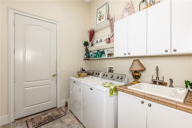 clothes washing area with washing machine and dryer, sink, and cabinets