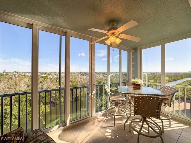 sunroom / solarium with a water view and ceiling fan