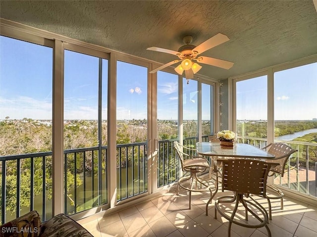 sunroom featuring a water view and ceiling fan