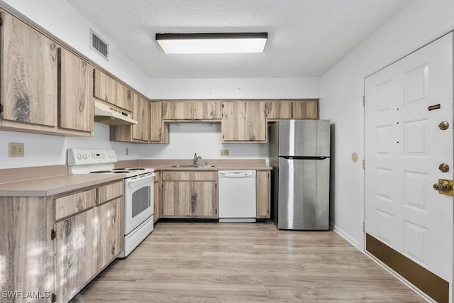 kitchen featuring a textured ceiling, white appliances, light hardwood / wood-style flooring, and sink