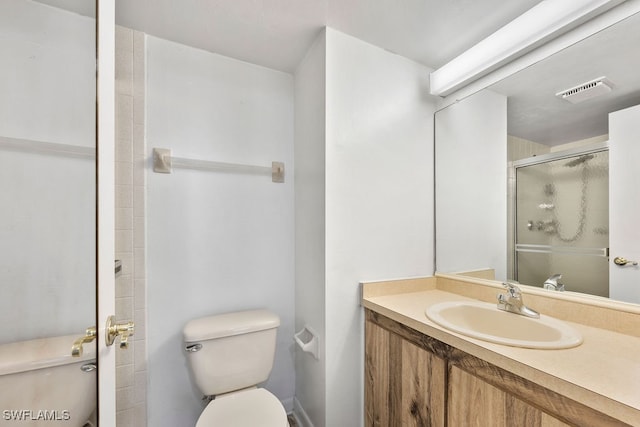 bathroom with vanity, a shower with shower door, and toilet