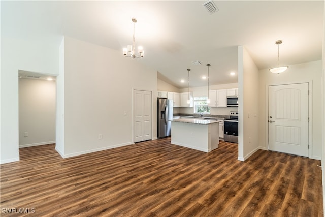 kitchen with stainless steel appliances, lofted ceiling, a center island, white cabinets, and decorative light fixtures