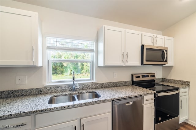 kitchen with white cabinets, appliances with stainless steel finishes, wood-type flooring, and sink