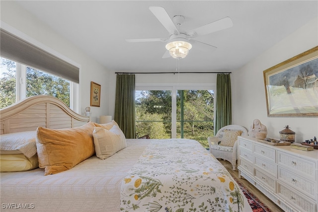 bedroom featuring hardwood / wood-style flooring, ceiling fan, access to outside, and multiple windows