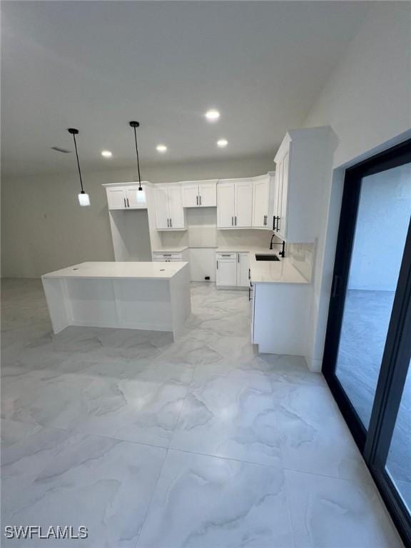 kitchen with white cabinetry, sink, and decorative light fixtures