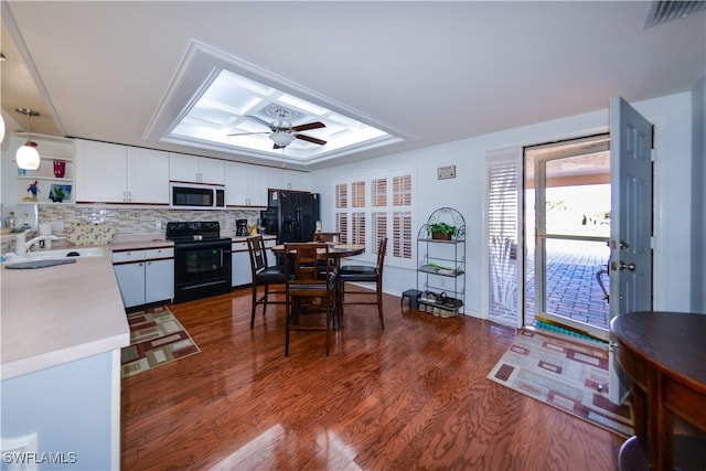 kitchen with hanging light fixtures, dark hardwood / wood-style flooring, white cabinets, and black appliances