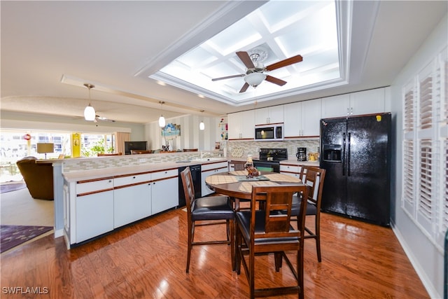 kitchen with white cabinetry, kitchen peninsula, pendant lighting, wood-type flooring, and black appliances