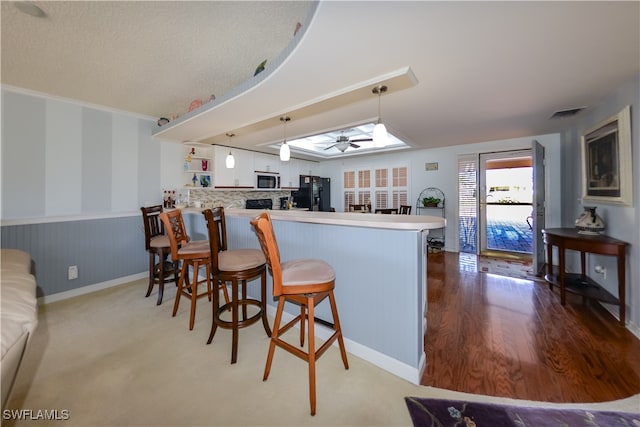 kitchen featuring pendant lighting, white cabinets, a kitchen breakfast bar, black refrigerator, and kitchen peninsula