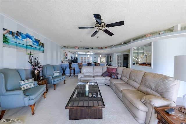 living room featuring ceiling fan, light colored carpet, and a textured ceiling