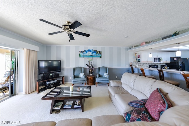 carpeted living room with ceiling fan, ornamental molding, and a textured ceiling