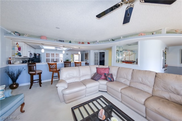 living room featuring ceiling fan and a textured ceiling