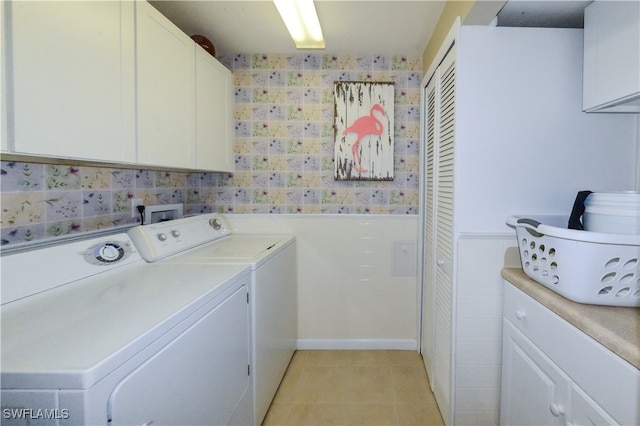 laundry room featuring washer and dryer, cabinets, and light tile patterned flooring