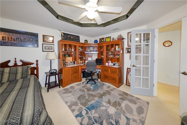 carpeted bedroom with a raised ceiling and ceiling fan