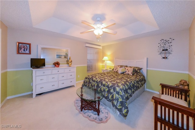 carpeted bedroom featuring a textured ceiling, a raised ceiling, and ceiling fan