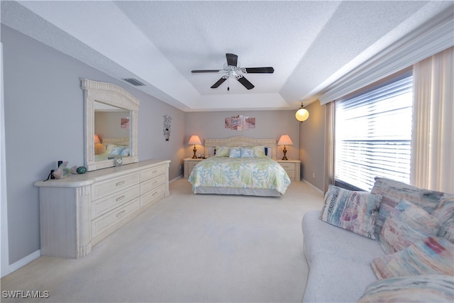 carpeted bedroom with a tray ceiling, ceiling fan, and a textured ceiling