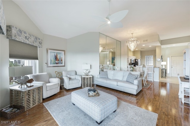 living room with ceiling fan with notable chandelier, vaulted ceiling, and wood-type flooring