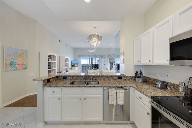 kitchen featuring stainless steel appliances, sink, stone countertops, an inviting chandelier, and white cabinetry