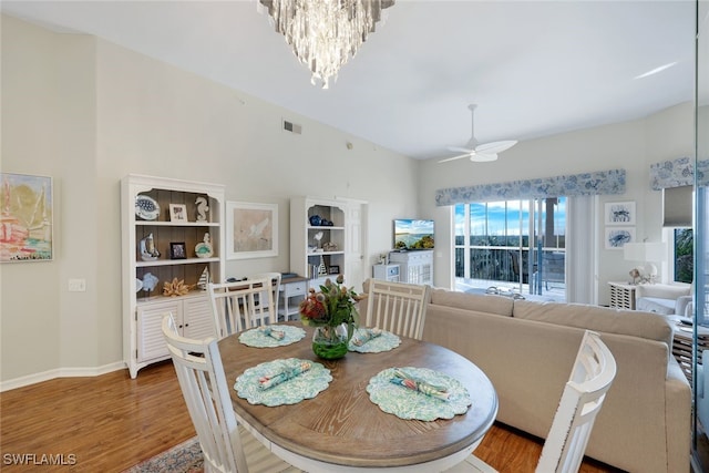 dining space with hardwood / wood-style floors and ceiling fan with notable chandelier