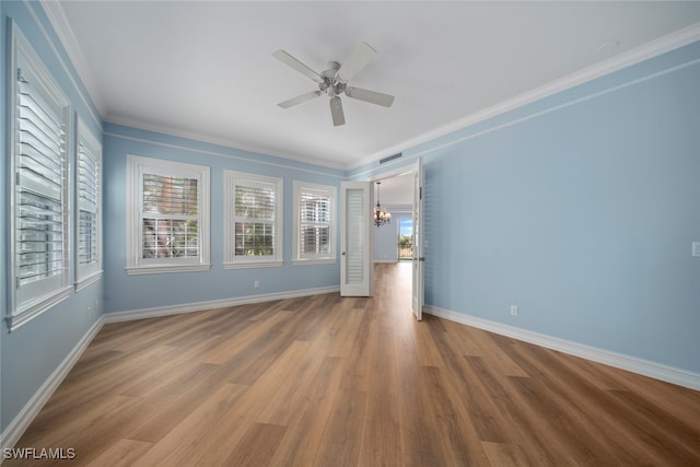 spare room featuring ceiling fan with notable chandelier, hardwood / wood-style flooring, and ornamental molding