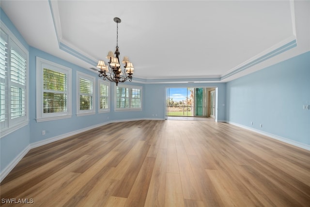 interior space with a notable chandelier, a raised ceiling, ornamental molding, and light hardwood / wood-style flooring