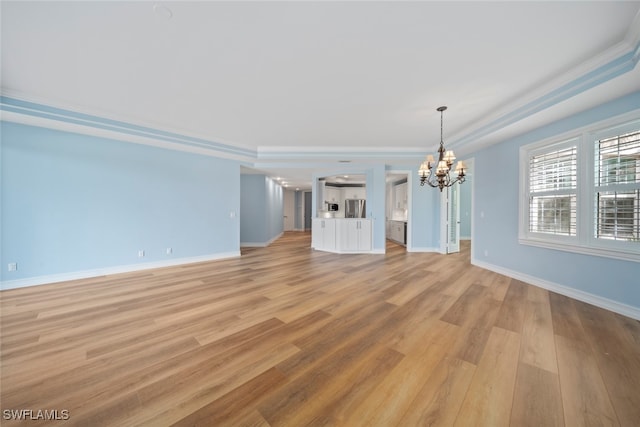 unfurnished living room featuring crown molding, light hardwood / wood-style flooring, and an inviting chandelier