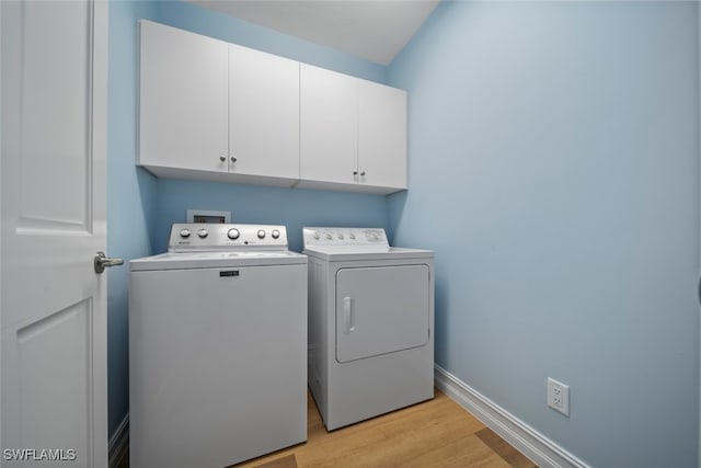 washroom featuring cabinets, light wood-type flooring, and separate washer and dryer