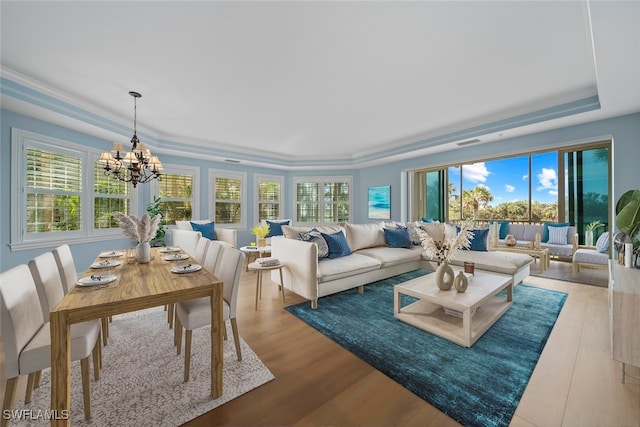 sunroom featuring a tray ceiling, plenty of natural light, and a notable chandelier