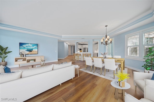 living room with crown molding, an inviting chandelier, and hardwood / wood-style flooring