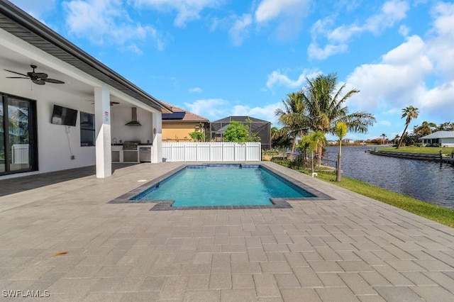 view of pool with an outdoor kitchen, a water view, ceiling fan, and a patio area