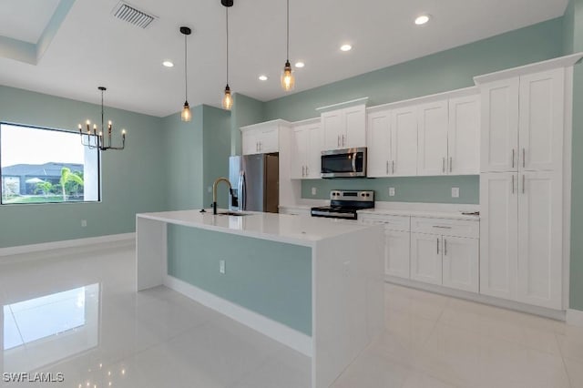 kitchen with hanging light fixtures, stainless steel appliances, light tile patterned floors, a center island with sink, and white cabinets