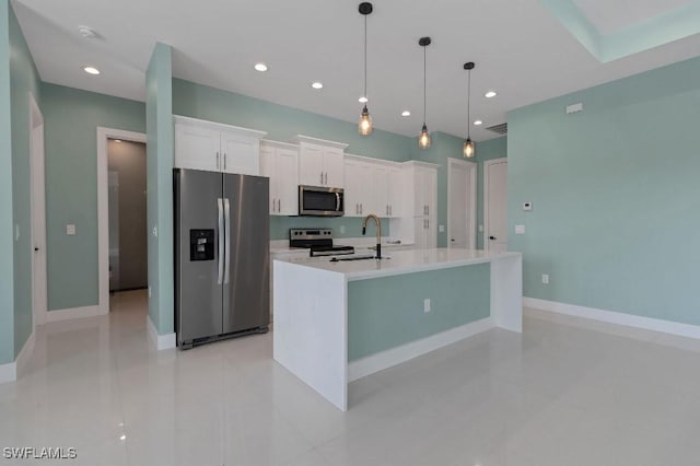 kitchen with white cabinets, appliances with stainless steel finishes, a kitchen island with sink, and pendant lighting