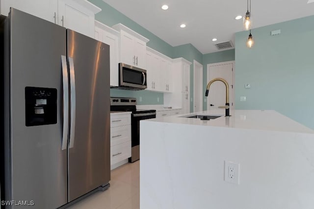 kitchen featuring sink, hanging light fixtures, an island with sink, white cabinets, and appliances with stainless steel finishes