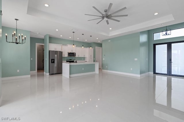 interior space featuring a raised ceiling, white cabinetry, hanging light fixtures, and appliances with stainless steel finishes