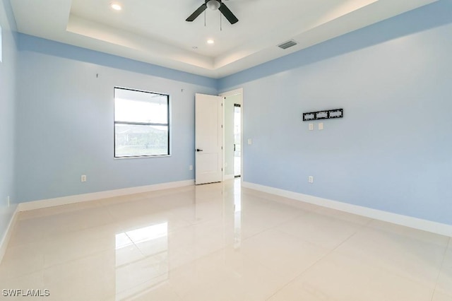 spare room featuring light tile patterned floors, a raised ceiling, and ceiling fan