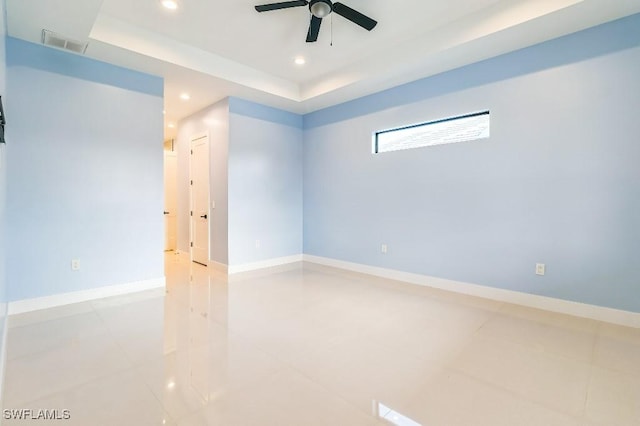 unfurnished room with ceiling fan and a tray ceiling