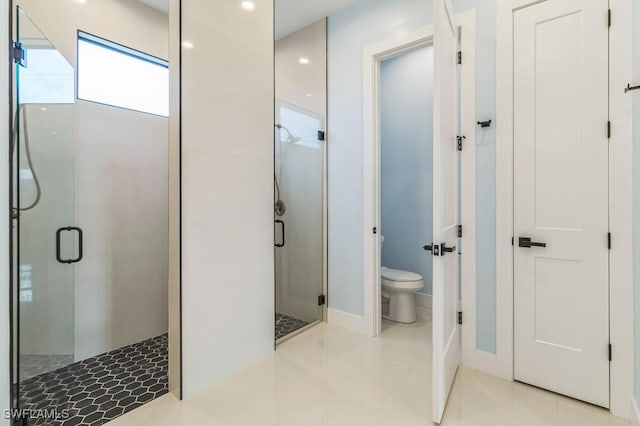 bathroom featuring tile patterned floors, toilet, and a shower with door